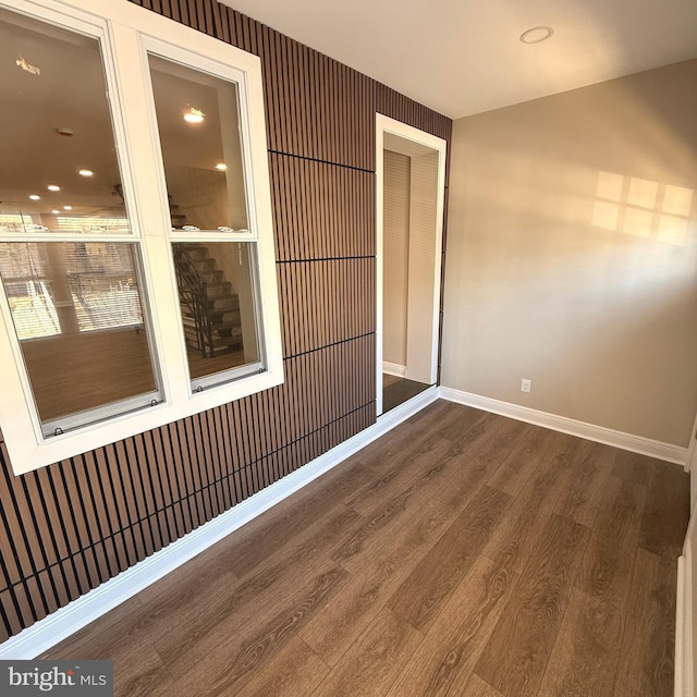 spare room featuring baseboards and wood finished floors