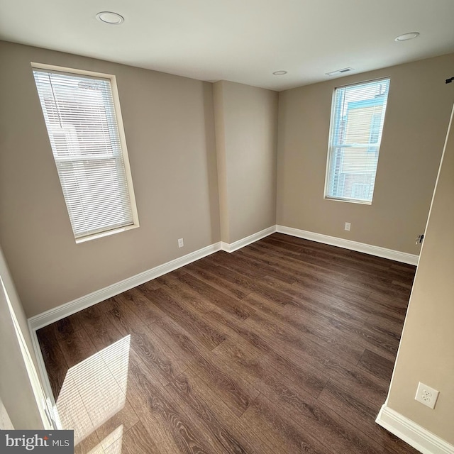 spare room featuring recessed lighting, baseboards, and dark wood finished floors