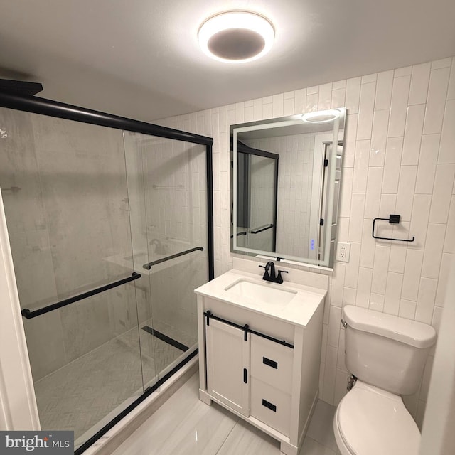 full bathroom with vanity, a stall shower, toilet, and tile walls