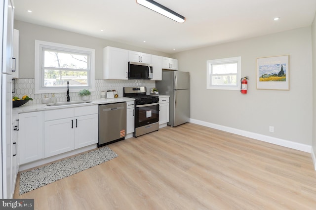kitchen with baseboards, appliances with stainless steel finishes, a sink, and tasteful backsplash