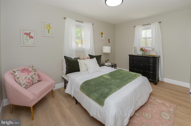 bedroom featuring light wood-type flooring, baseboards, and multiple windows
