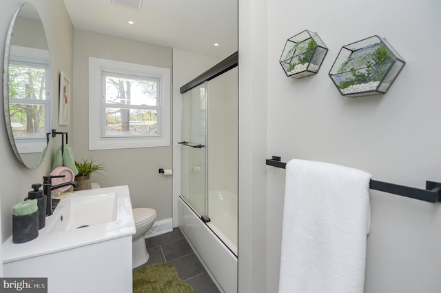 bathroom with vanity, baseboards, tile patterned floors, toilet, and shower / bath combination with glass door