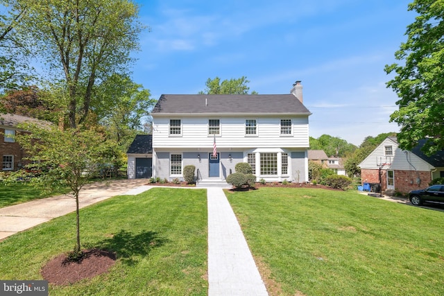 colonial home featuring a garage, a front lawn, driveway, and a chimney