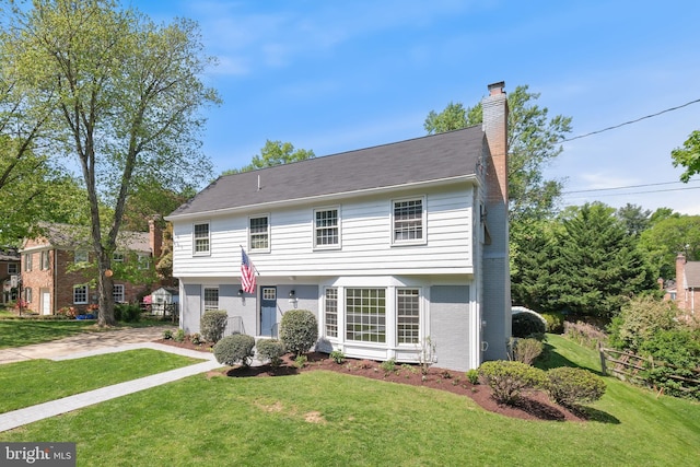 view of front of home featuring brick siding, fence, a chimney, and a front lawn