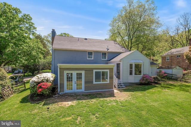 back of house with french doors, a chimney, a lawn, and entry steps