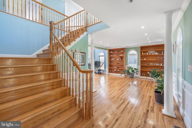 foyer entrance featuring ornate columns, stairs, wood finished floors, ornamental molding, and recessed lighting