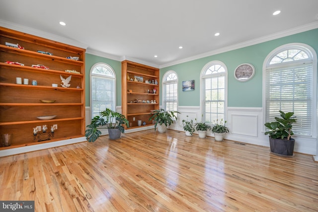 living area featuring a wainscoted wall, ornamental molding, wood finished floors, recessed lighting, and a decorative wall