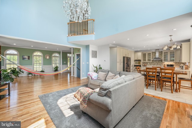 living room with a chandelier, light wood-style floors, recessed lighting, and a high ceiling
