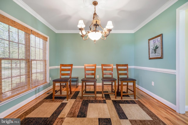 dining room with wood finished floors, a chandelier, ornamental molding, and baseboards