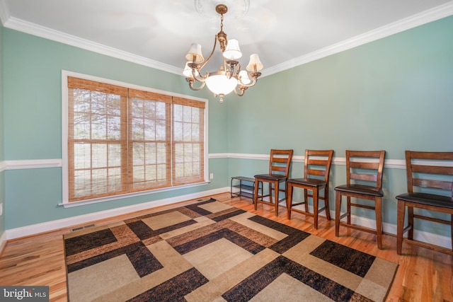 living area with crown molding, a chandelier, wood finished floors, and baseboards