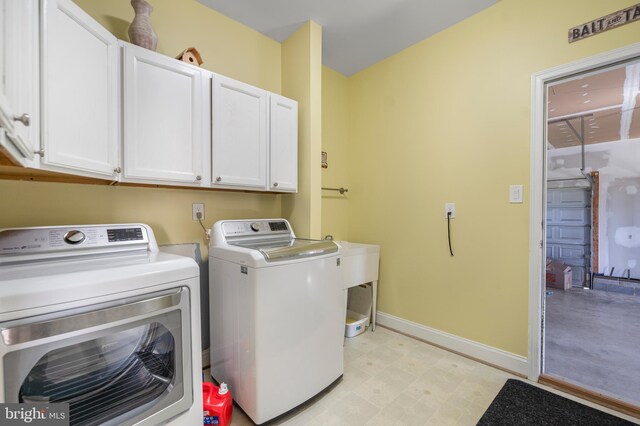 clothes washing area with cabinet space, independent washer and dryer, baseboards, and light flooring
