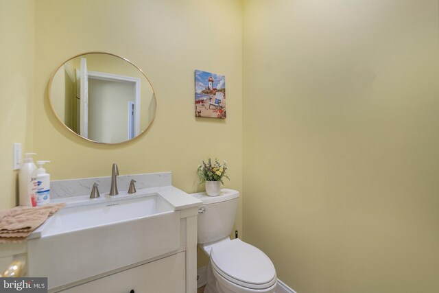 bathroom featuring toilet, vanity, and baseboards