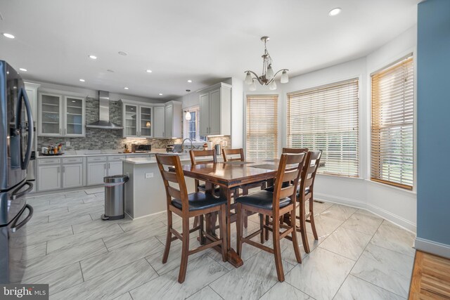 dining area with a chandelier, healthy amount of natural light, baseboards, recessed lighting, and light marble finish flooring
