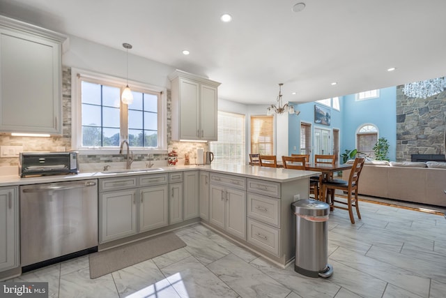 kitchen with stainless steel dishwasher, a sink, a chandelier, light countertops, and recessed lighting