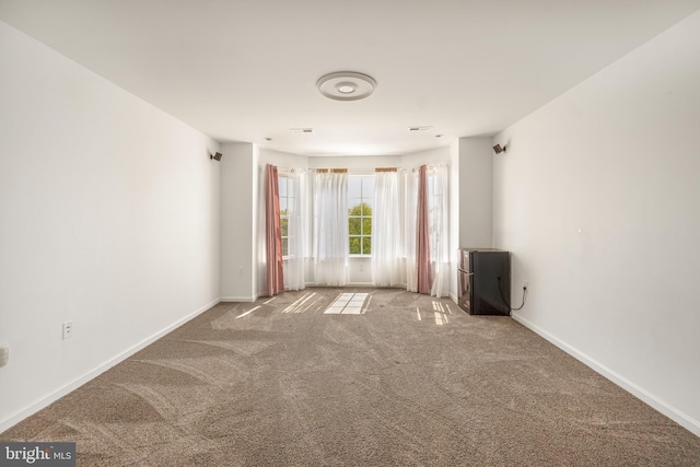 carpeted spare room featuring baseboards