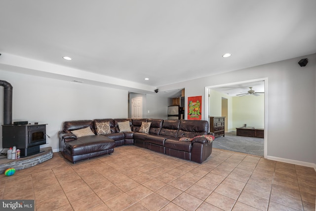 living area with recessed lighting, ceiling fan, light tile patterned flooring, a wood stove, and baseboards