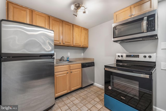 kitchen with stainless steel appliances, a sink, baseboards, light countertops, and light flooring
