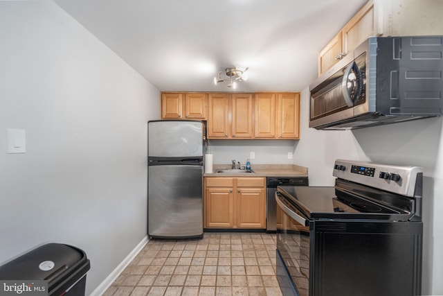 kitchen featuring appliances with stainless steel finishes, a sink, baseboards, light countertops, and light brown cabinets