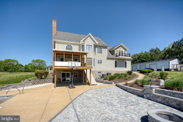 view of front of property with a balcony, stairs, a patio area, a chimney, and stone siding