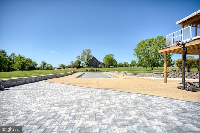 view of basketball court with an outdoor pool and a lawn