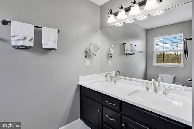 full bathroom featuring double vanity, baseboards, and a sink