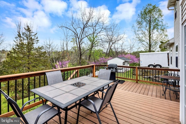 deck featuring a storage unit, an outbuilding, outdoor dining area, and a grill