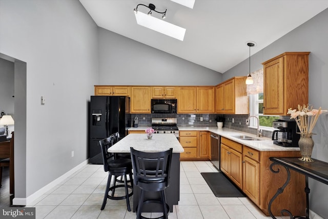kitchen with a sink, light countertops, backsplash, a skylight, and black appliances