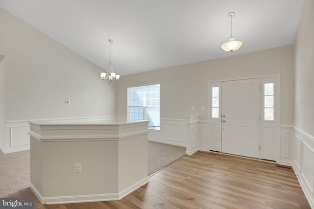 7438 Wildseed Pl, Hughesville, MD 20637 - foyer entrance featuring an inviting chandelier, wainscoting, a decorative wall, light wood-style flooring, and vaulted ceiling