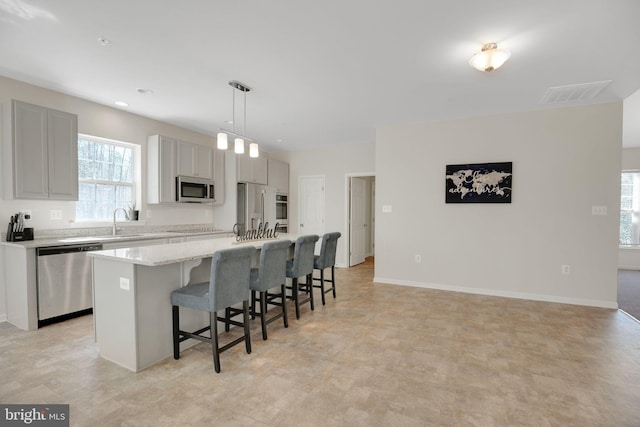 7438 Wildseed Pl, Hughesville, MD 20637 - kitchen featuring appliances with stainless steel finishes, a healthy amount of sunlight, a kitchen breakfast bar, and a center island with sink