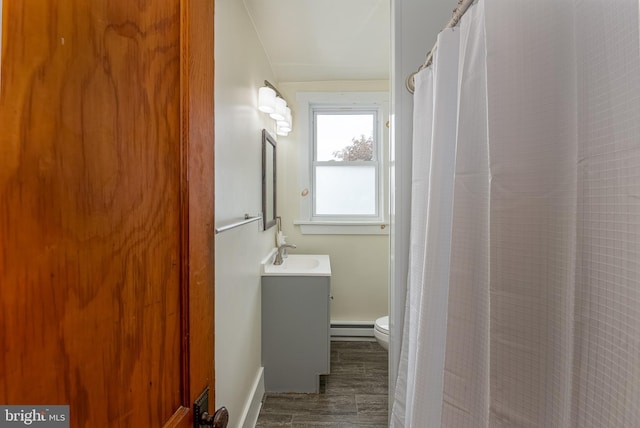 full bath featuring vanity, wood finished floors, toilet, a shower with shower curtain, and a baseboard radiator