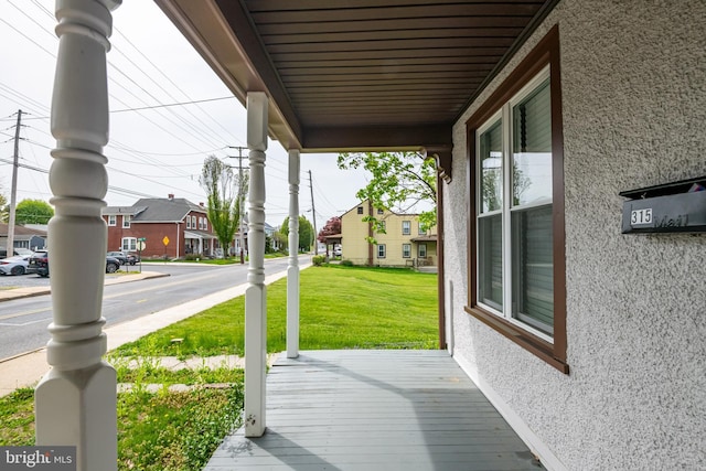 wooden deck with a porch, a lawn, and a residential view