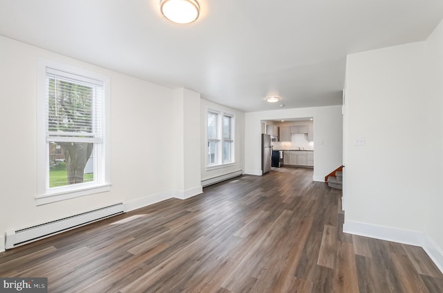 unfurnished living room featuring a baseboard radiator, dark wood-style floors, a wealth of natural light, and baseboard heating