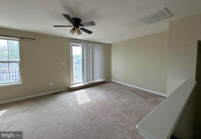carpeted empty room with visible vents, baseboards, and ceiling fan