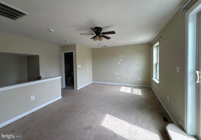 interior space featuring carpet flooring, ceiling fan, visible vents, and baseboards