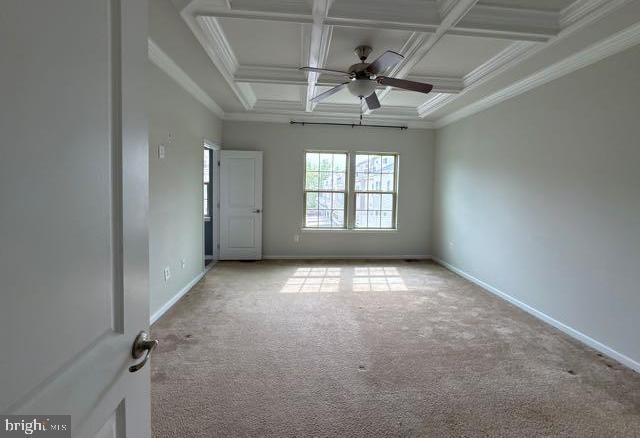 empty room featuring crown molding, carpet, ceiling fan, and coffered ceiling