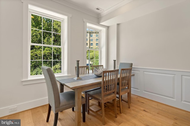 dining area with light wood-type flooring, ornamental molding, a wealth of natural light, and visible vents
