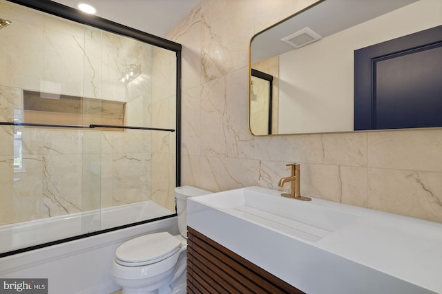 full bathroom with vanity, shower / bath combination with glass door, toilet, tile walls, and tasteful backsplash