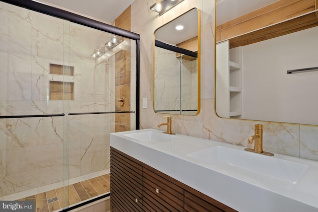 bathroom featuring double vanity, a tile shower, and a sink