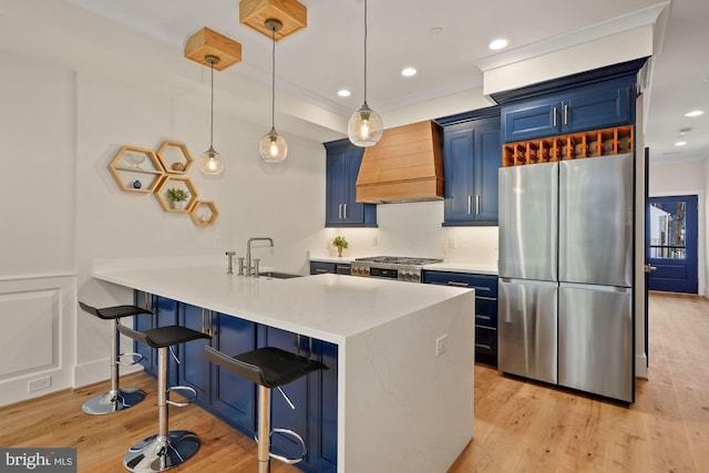 kitchen featuring a sink, premium range hood, a kitchen bar, blue cabinets, and appliances with stainless steel finishes