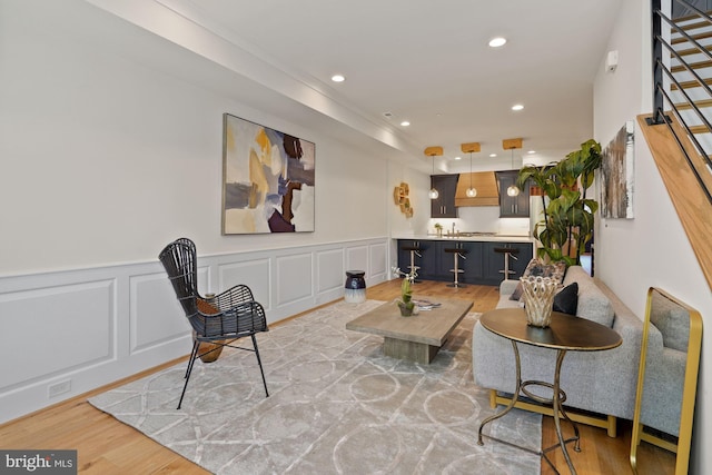 living area featuring light wood-style floors, recessed lighting, stairs, and a decorative wall