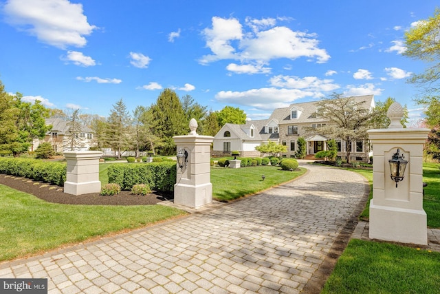 view of community featuring decorative driveway and a yard