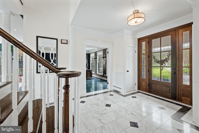 entrance foyer with crown molding, a baseboard radiator, marble finish floor, a decorative wall, and stairs