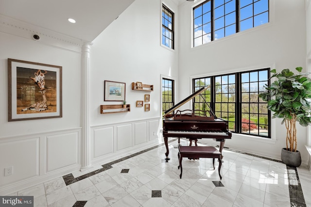 sitting room featuring a high ceiling, a wainscoted wall, marble finish floor, and a decorative wall