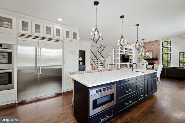 kitchen with an inviting chandelier, white cabinetry, a sink, dark wood finished floors, and appliances with stainless steel finishes
