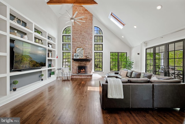 living area with a ceiling fan, a fireplace, wood finished floors, and high vaulted ceiling