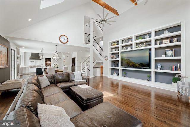living room with stairs, wood finished floors, high vaulted ceiling, a chandelier, and built in shelves