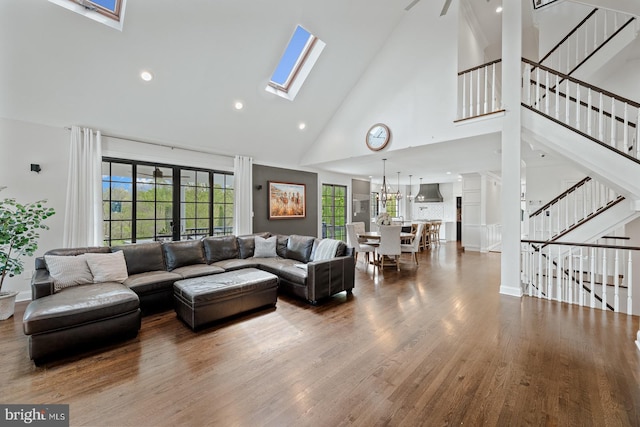living room with a skylight, wood finished floors, stairway, high vaulted ceiling, and recessed lighting