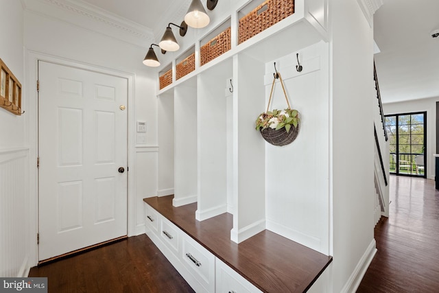 mudroom with dark wood-type flooring, baseboards, and crown molding