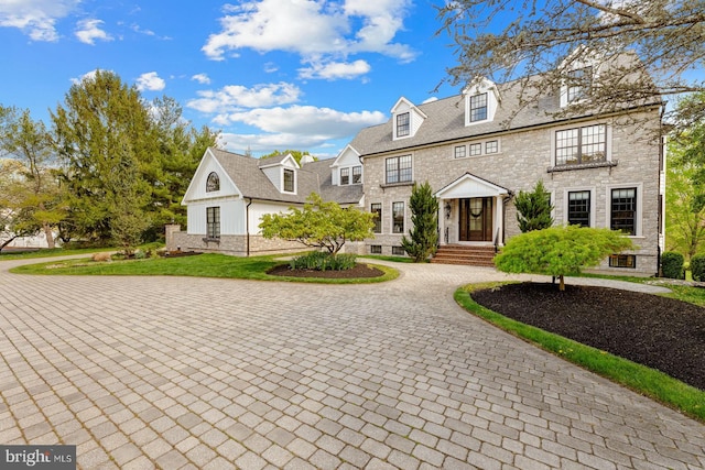 view of front of property with curved driveway and stone siding