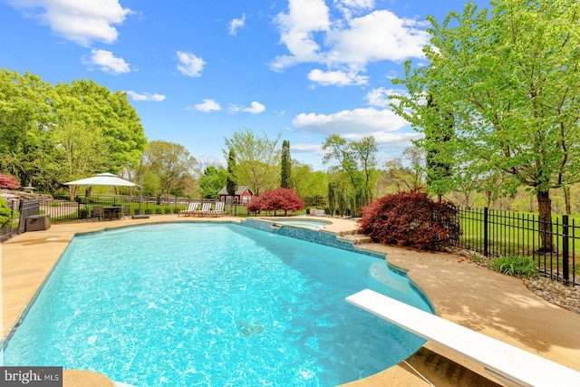 view of swimming pool with fence, a diving board, a pool with connected hot tub, and a patio area
